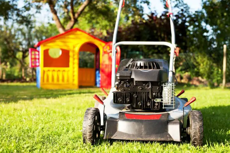 Front view of a lawn mower on a well-kept lawn, possibly experiencing issues like burning oil.
