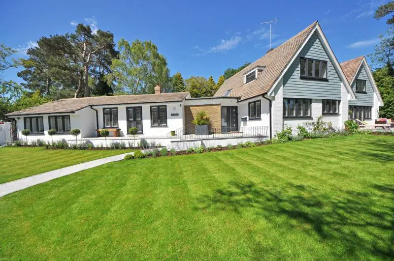 White and blue-trimmed house with a manicured lawn, showcasing an ideal setting for lawn rolling.