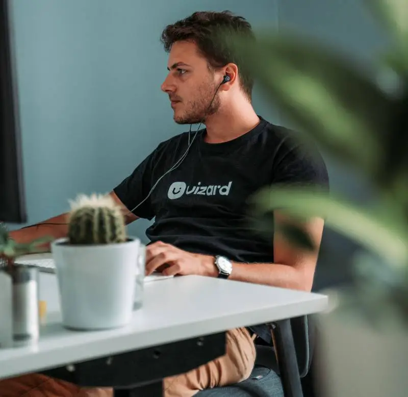 Person at a desk with a small cactus, illustrating a low-maintenance plant that is good for office environments.