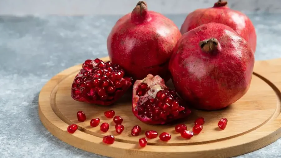 Fruits With Big Seeds 1 Ripe pomegranates with large, juicy seeds on a wooden board, a vivid example of fruits with big seeds.