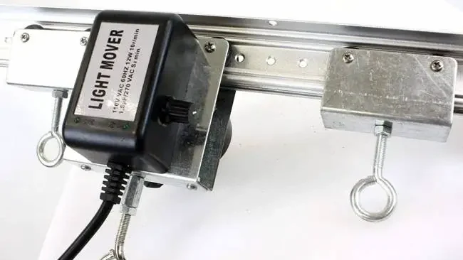 Light Movers - Are They Worth It for Growers? 1 Close-up of a light mover system with a metallic rail, adjustable motor unit, and cables, vital for optimizing indoor plant lighting.